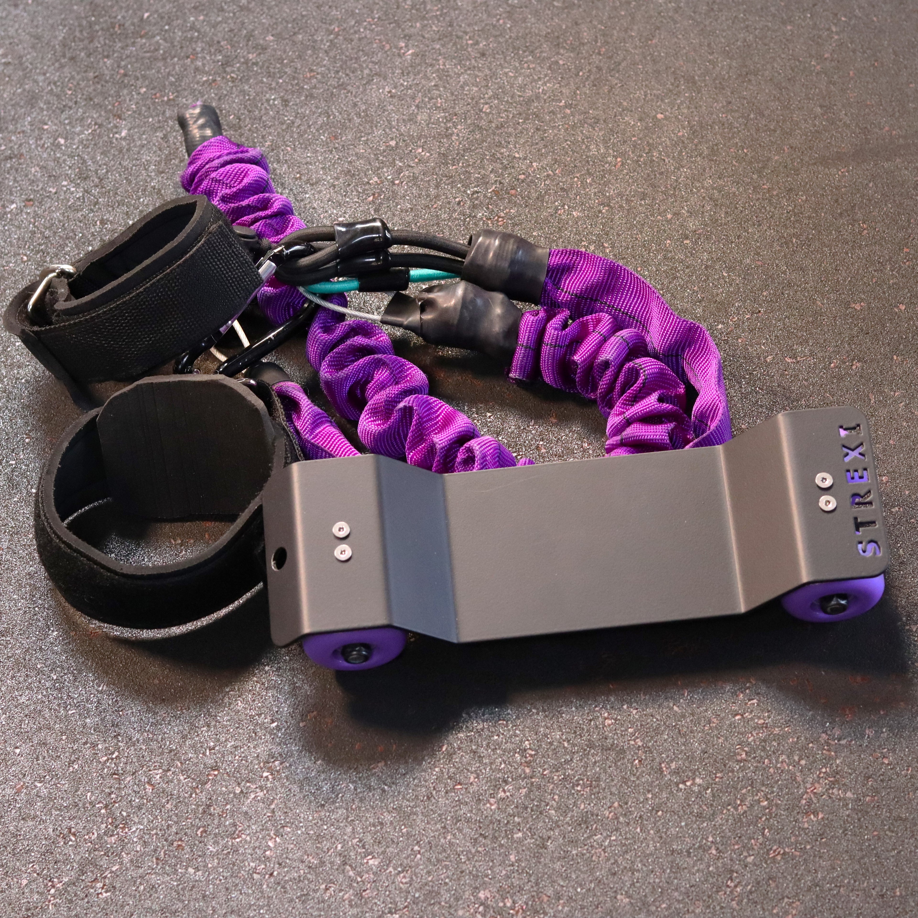 A Strexi stretching device with purple resistance bands, adjustable safety harness, and comfortable ankle straps on a dark background.